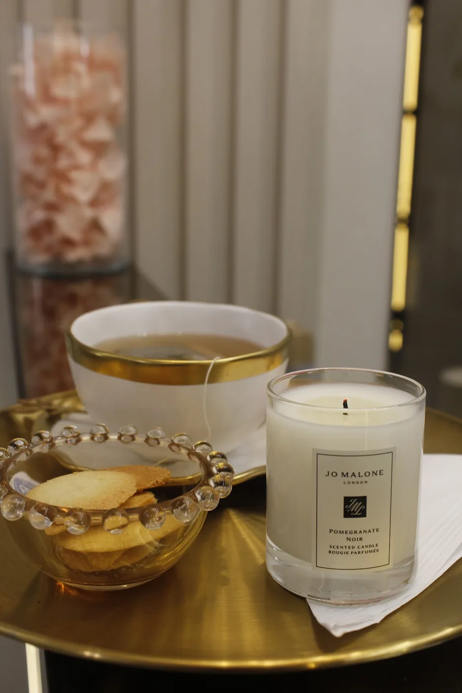 Bandeja dourada com xícara de chá, biscoitos e vela perfumada
